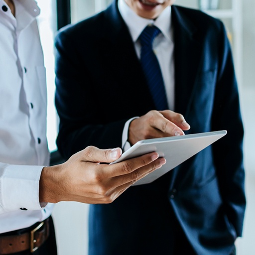 People in suits looking at a tablet — supply chain consulting services
